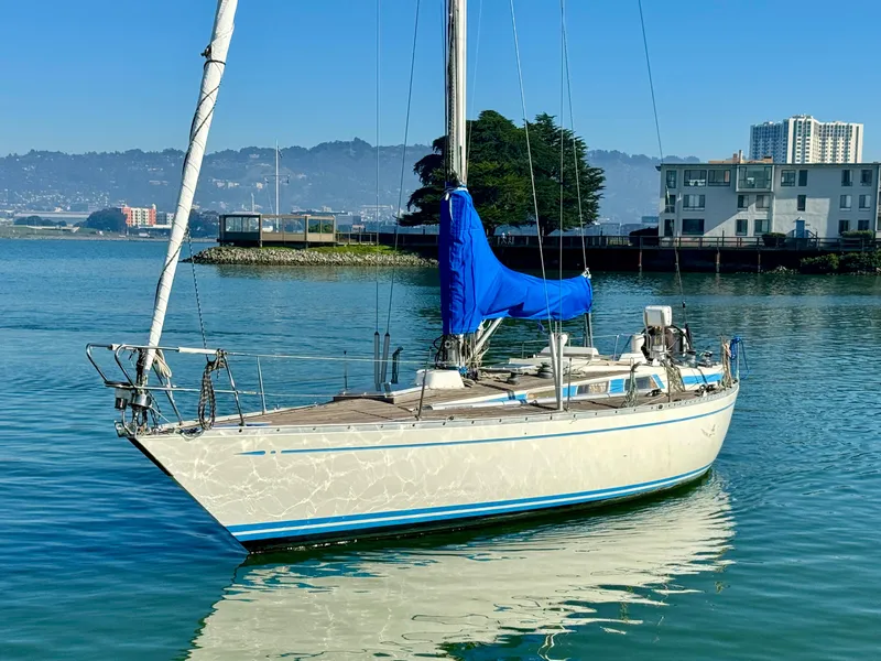 The Image of 1974 Nautor Swan 38 sailboat with blue sail cover on calm water. - 0