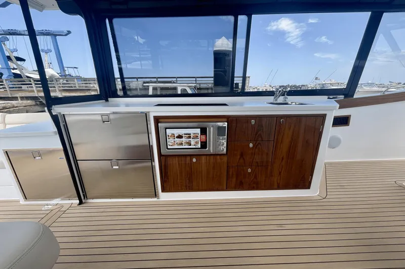 Slide: The Image of 2024 MJM 4 yacht interior with kitchenette, featuring wood cabinetry and stainless steel appliances. - 7