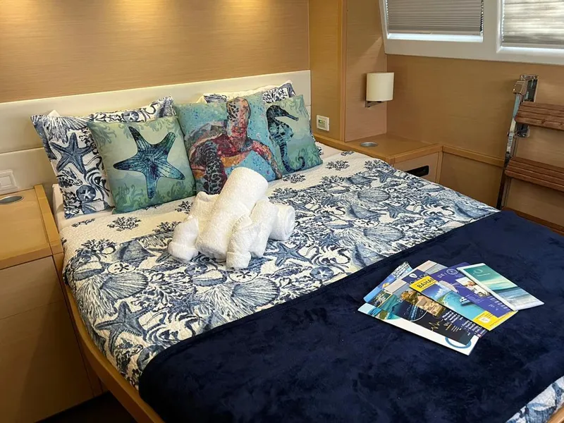 Slide: The Image of Luxurious bedroom on 2015 Lagoon 620 yacht with nautical-themed decor and reading materials. - 2