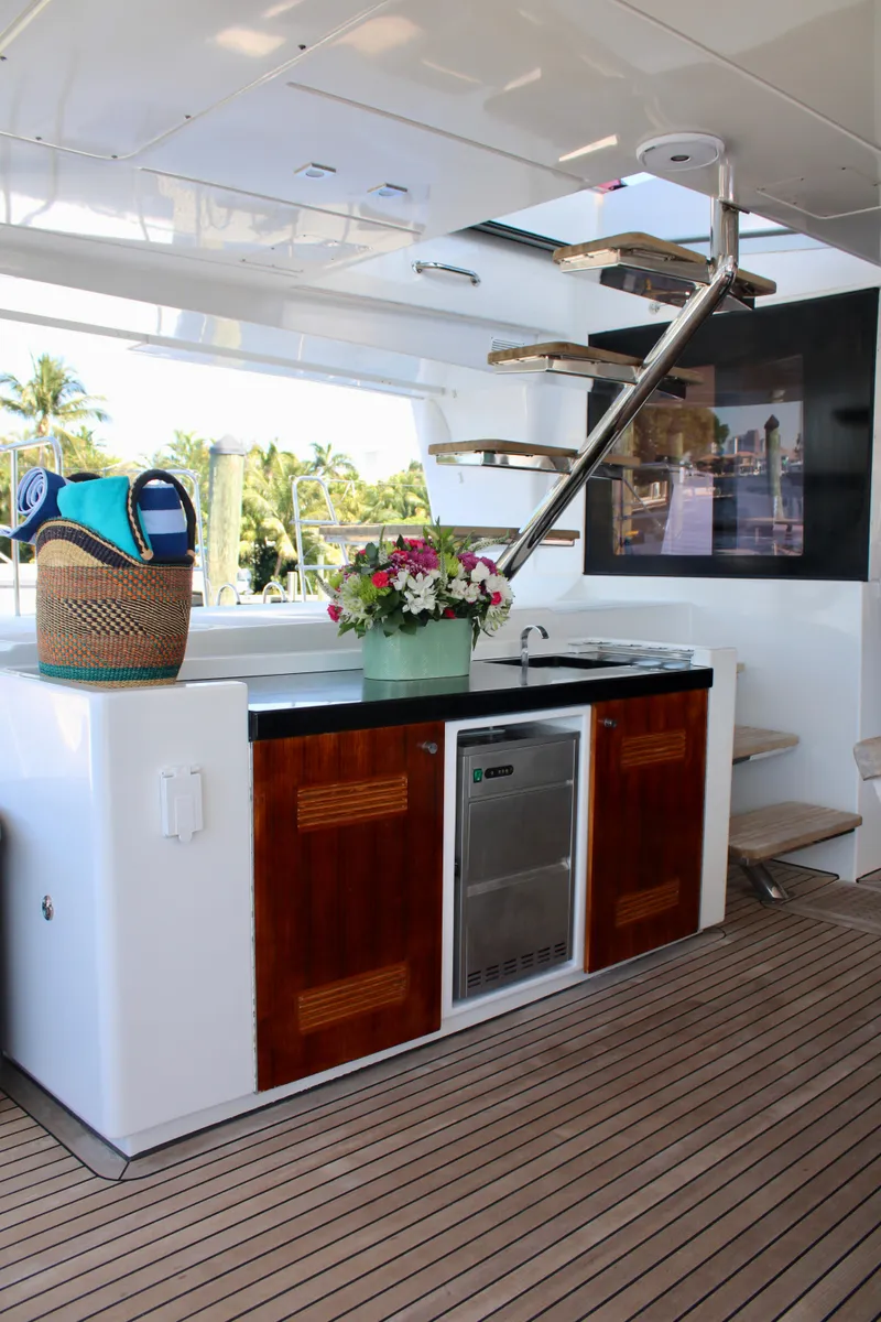 Slide: The Image of Lagoon 620 2015 yacht interior with kitchenette, wooden cabinets, and spiral staircase. - 26