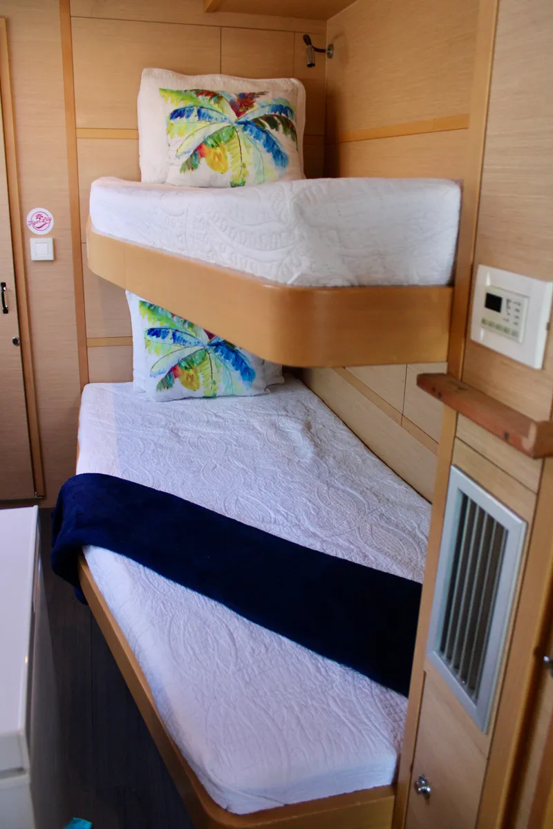 Slide: The Image of Bunk beds in the 2015 Lagoon 620 catamaran cabin with tropical-themed pillows. - 49