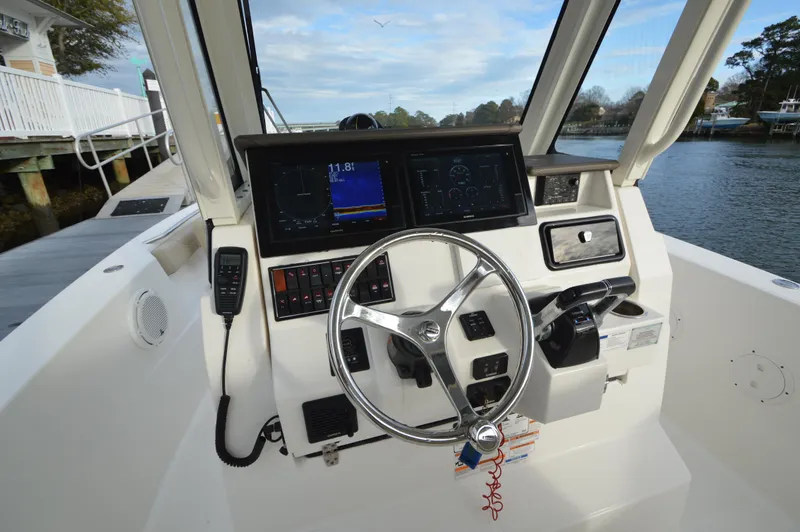 Slide: The Image of 2019 Pursuit S 288 Sport boat helm with steering wheel, navigation screens, and controls. - 17