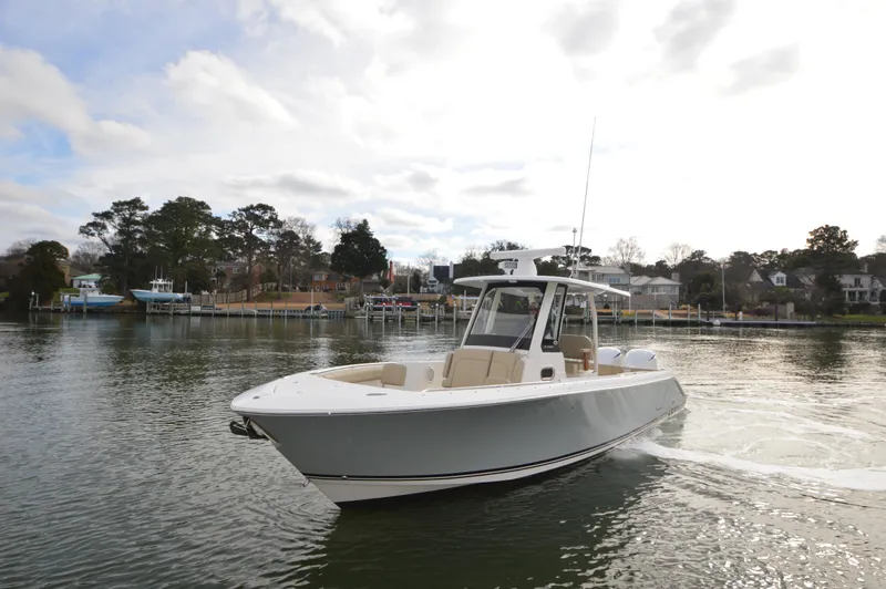 Slide: The Image of 2019 Pursuit S 288 Sport boat cruising on a calm lake near a residential area. - 3