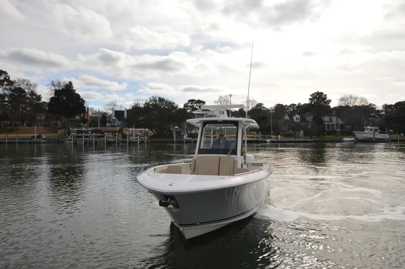 Slide: The Image of 2019 Pursuit S 288 Sport boat cruising on a calm river near a residential area. - 5