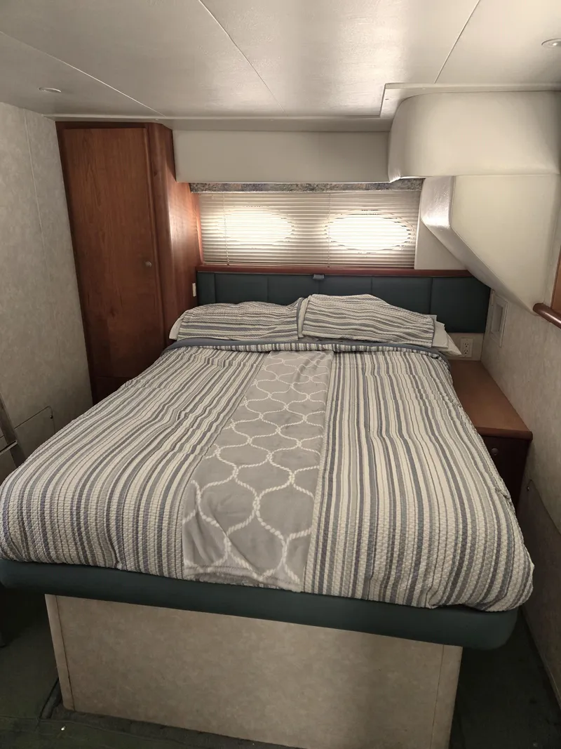 Slide: The Image of Cozy bedroom in 1997 Silverton 372 Motor Yacht with striped bedding and wooden accents. - 12