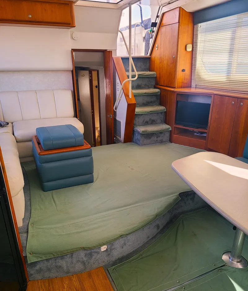 Slide: The Image of Interior of a 1997 Silverton 372 Motor Yacht with seating, stairs, and a small TV. - 2