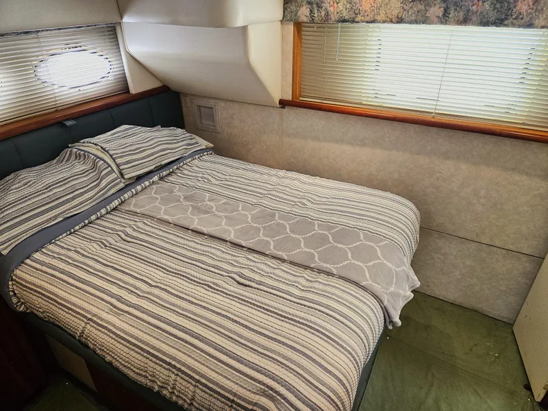Slide: The Image of 1997 Silverton 372 Motor Yacht bedroom with striped bedding and window blinds. - 9