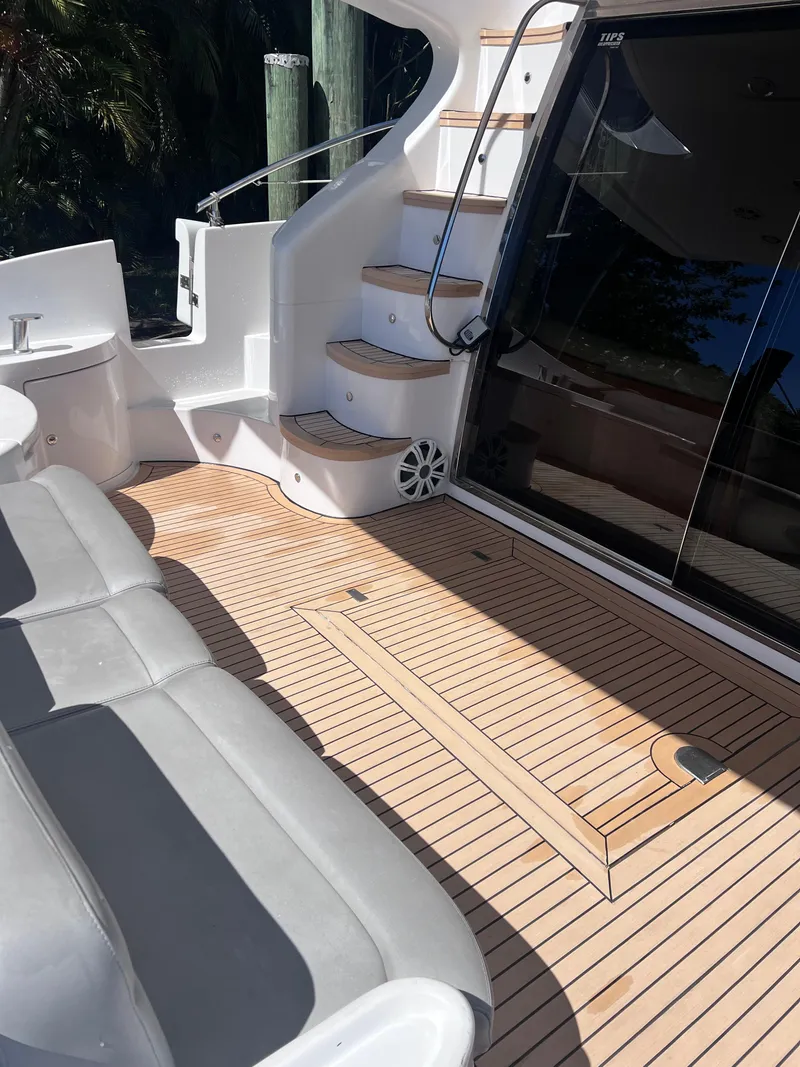 Slide: The Image of Azimut 55 Flybridge 2005 yacht deck with seating and stairs, featuring sleek design and wood finish. - 13