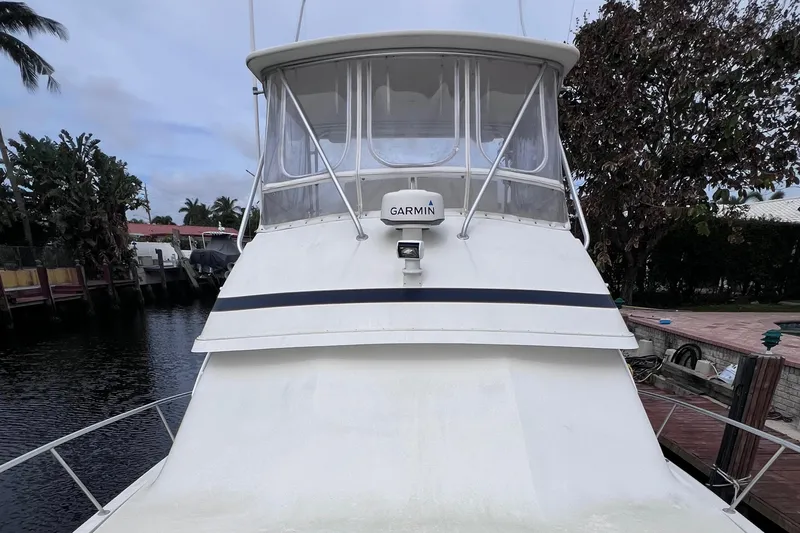 Slide: The Image of 1988 Bertram 43 Convertible boat docked near waterfront homes. - 10