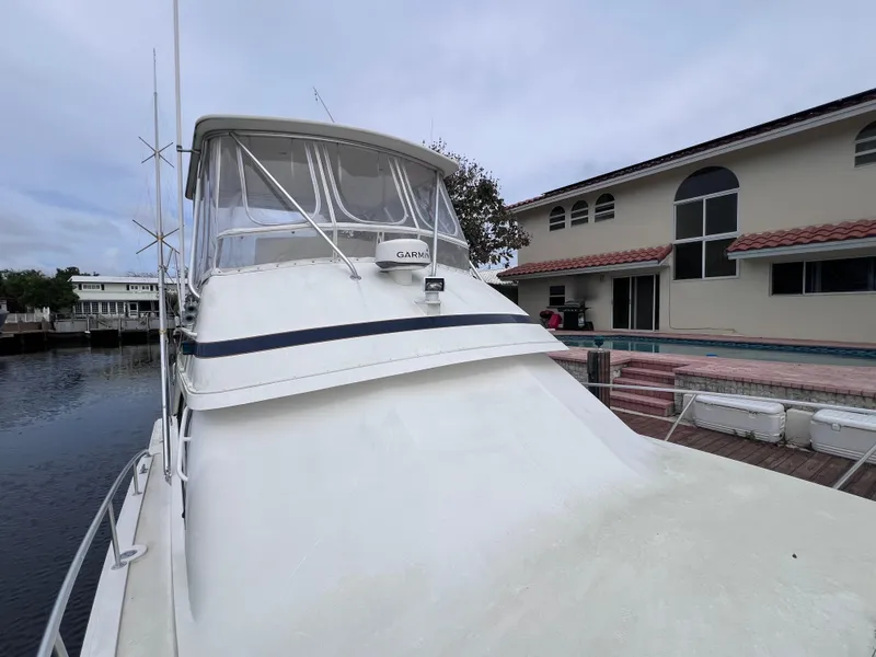 Slide: The Image of 1988 Bertram 43 Convertible yacht docked near waterfront homes. - 13