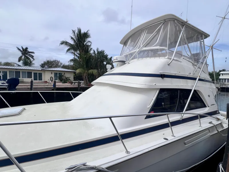 Slide: The Image of 1988 Bertram 43 Convertible yacht docked near waterfront homes. - 3