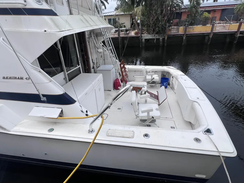 Slide: The Image of 1988 Bertram 43 Convertible boat docked, spacious deck, fishing chairs, and clean white exterior. - 4