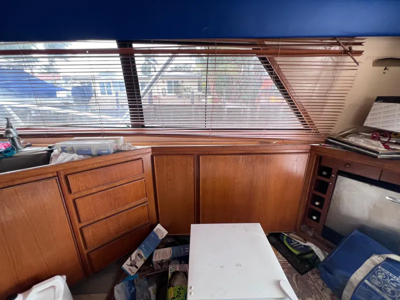 Slide: The Image of Interior of 1988 Bertram 43 Convertible boat with wooden cabinets and cluttered space. - 45