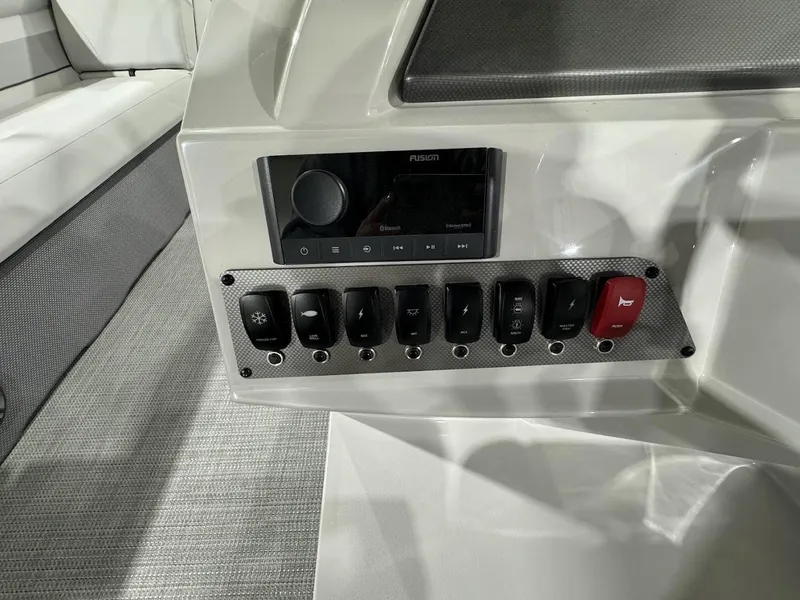 Slide: The Image of Control panel of 2024 Crest Classic LX 220 boat with switches and a Fusion stereo system. - 15