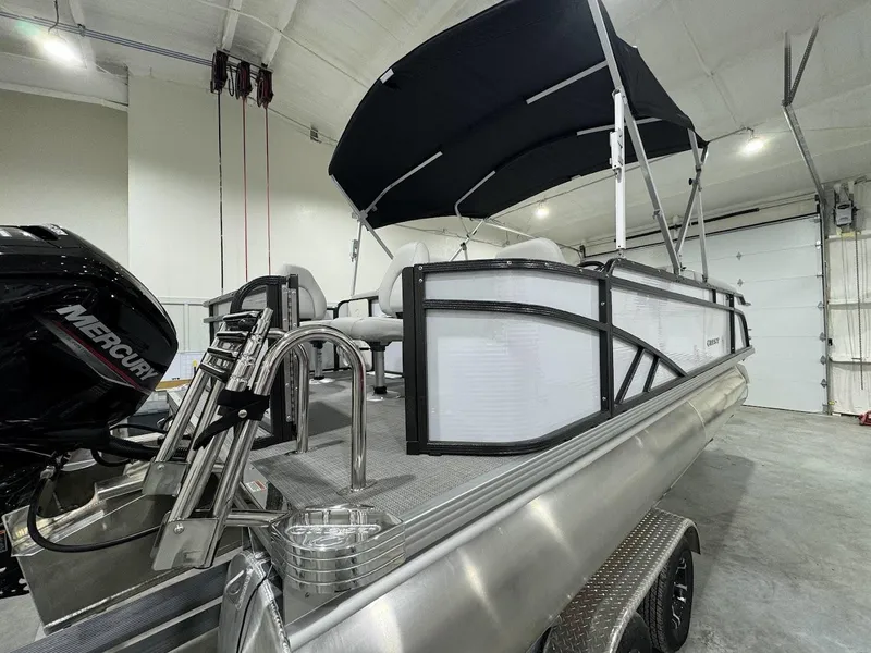 Slide: The Image of 2024 Crest Classic LX 220 pontoon boat with canopy in a showroom. - 2