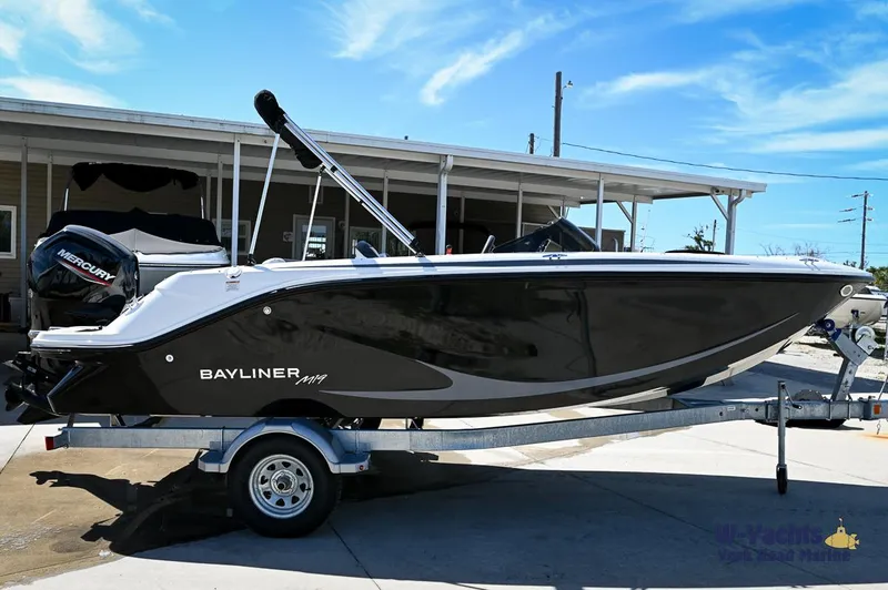 The Image of 2024 Bayliner M19 boat on trailer, side view, black hull, outdoor setting. - 0