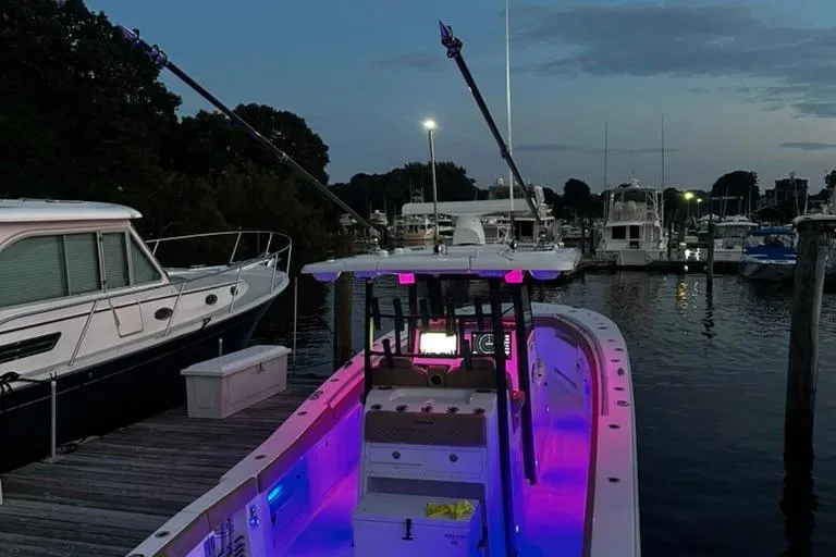 Slide: The Image of 2024 Caymas 341 CC boat docked at marina during twilight with vibrant interior lighting. - 16