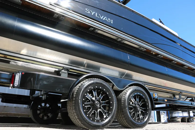Slide: The Image of 2024 Sylvan G5 CLZ DC pontoon boat on a trailer with black wheels. - 23