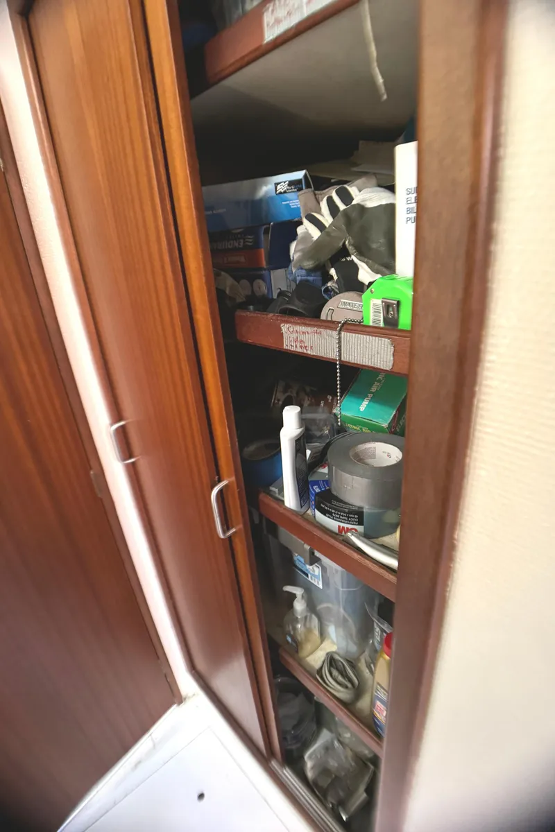 Slide: The Image of Storage cabinet on 1998 Catamaran Vision 51, filled with various tools and supplies. - 11