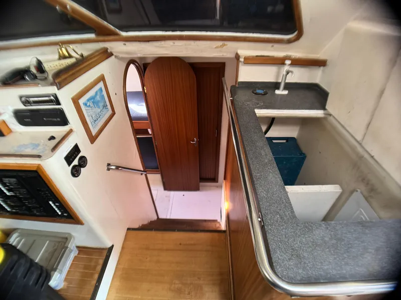 Slide: The Image of Interior view of 1998 Catamaran Vision 51, featuring a compact kitchen and wooden flooring. - 6