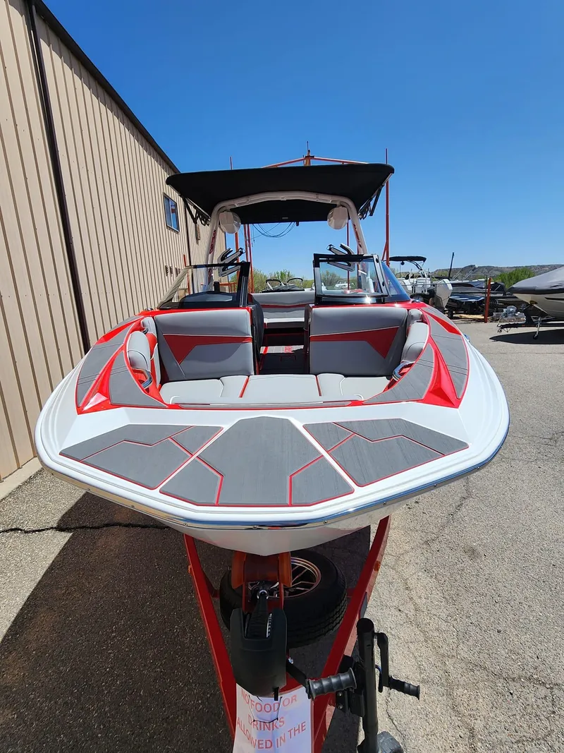 Slide: The Image of 2024 Supreme S240 boat with red and gray interior, parked outdoors. - 4