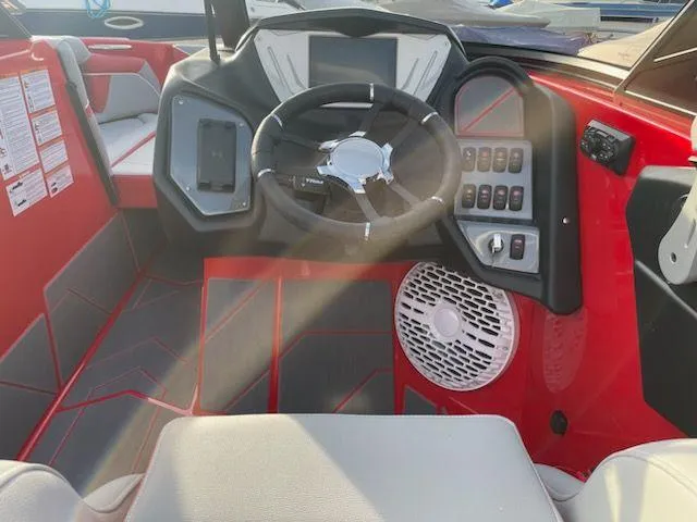 Slide: The Image of 2024 Supreme S240 boat dashboard with steering wheel, control panel, and red interior. - 8