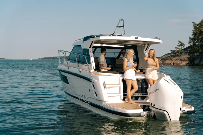 Slide: The Image of 2024 Aquador 250 HT boat with people enjoying a sunny day on the water. - 2