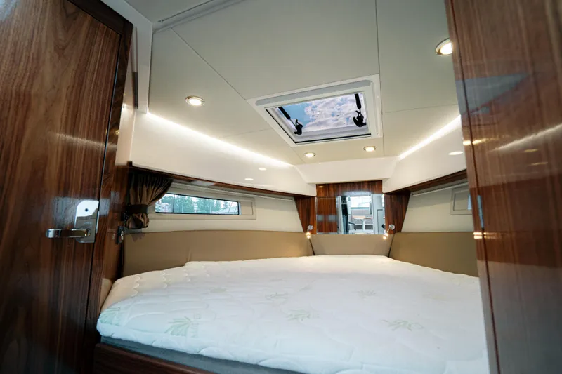 Slide: The Image of 2024 Aquador 250 HT cabin interior with skylight and wood paneling. - 3