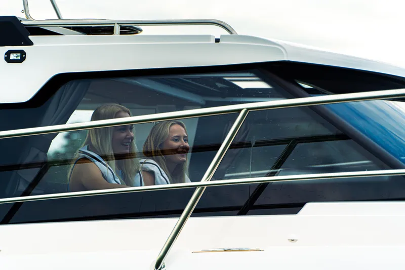 Slide: The Image of Two people inside a 2024 Aquador 250 HT boat, viewed through the window. - 7