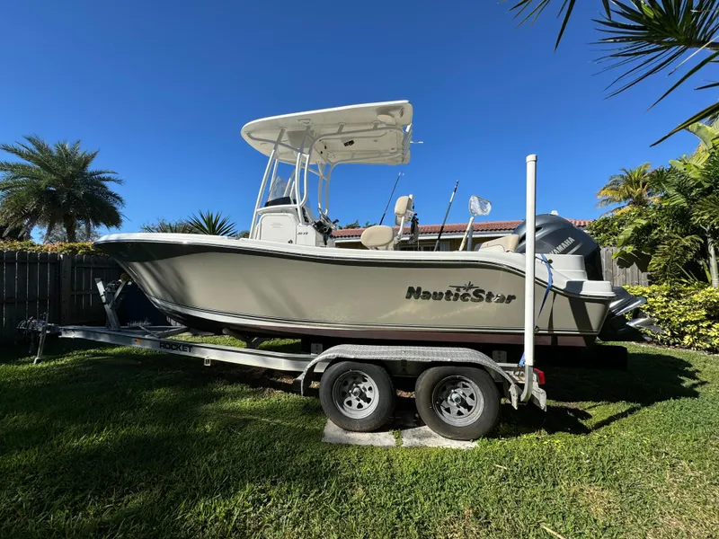 Slide: The Image of 2017 NauticStar 20 XS Offshore boat on a trailer in a grassy yard. - 2