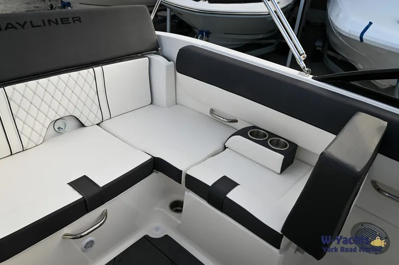 Slide: The Image of 2024 Bayliner DX2000 boat interior with white and black seating, cup holders, and storage. - 12