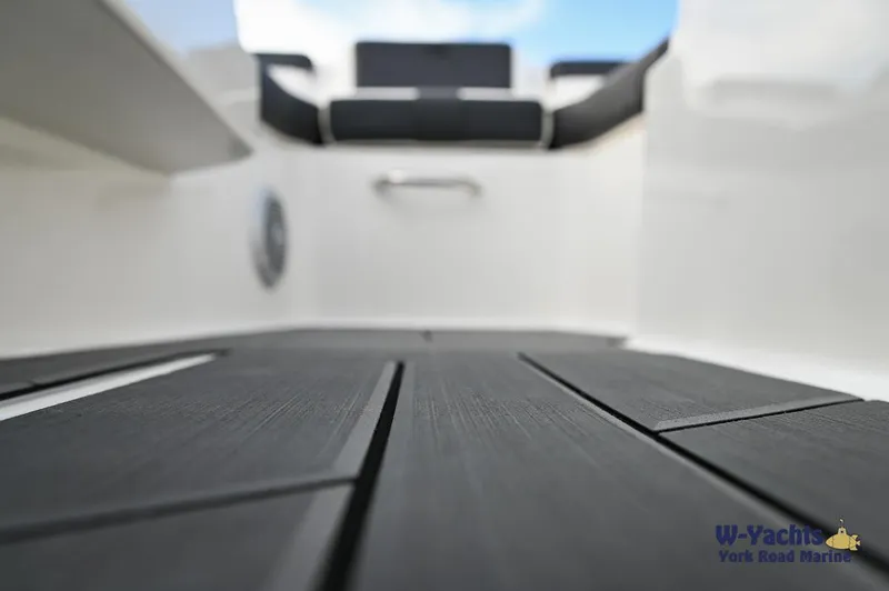 Slide: The Image of 2024 Bayliner DX2000 boat interior with black flooring and cushioned seating. - 21