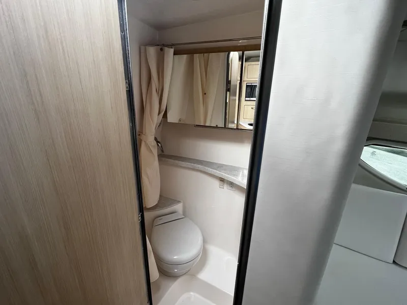 Slide: The Image of 2024 Regal 28 Express boat bathroom with toilet, mirror, and shower curtain. - 16
