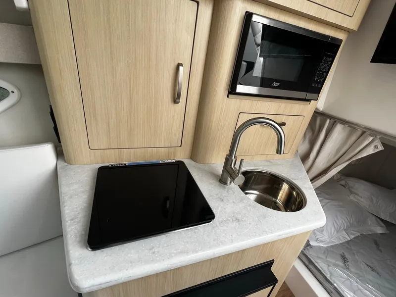 Slide: The Image of Compact kitchen area in 2024 Regal 28 Express boat with sink, microwave, and stove. - 19