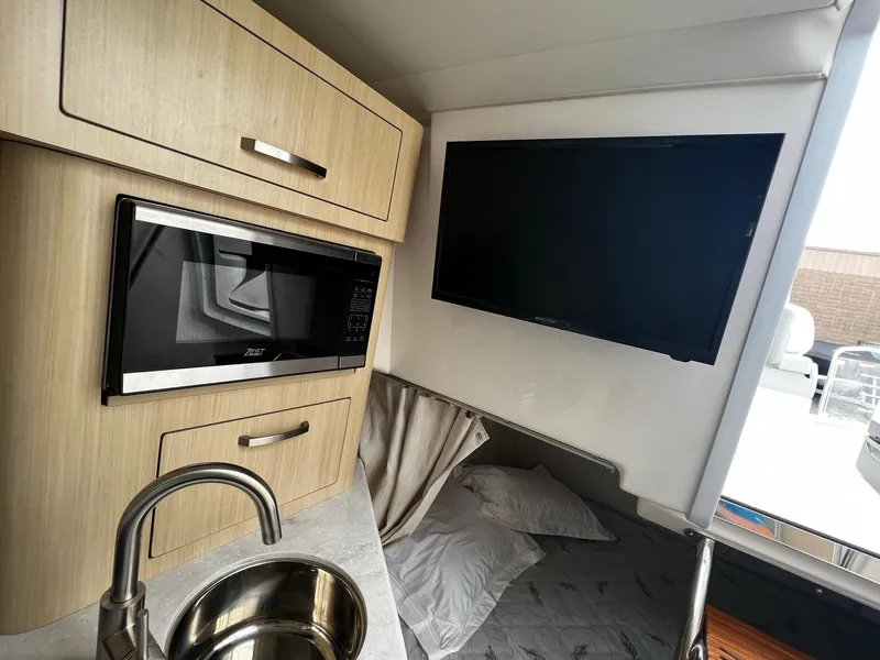 Slide: The Image of 2024 Regal 28 Express interior with microwave, sink, and TV. - 20