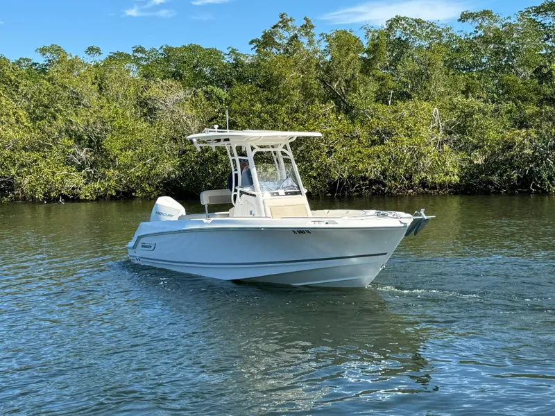 Slide: The Image of 2022 Boston Whaler 230 Outrage boat cruising on a calm river. - 2
