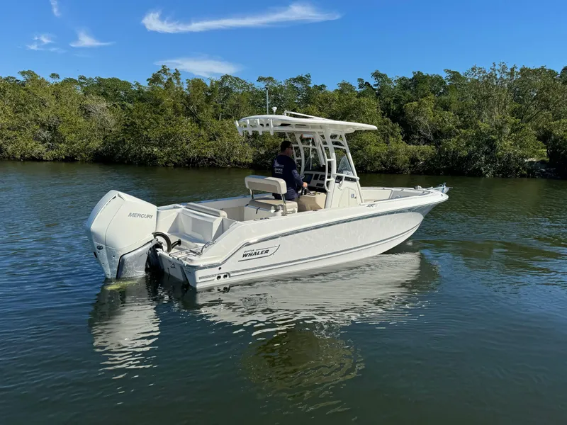 Slide: The Image of 2022 Boston Whaler 230 Outrage boat on calm water with lush green background. - 3