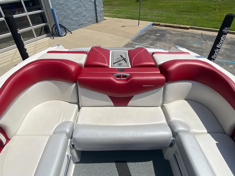 Slide: The Image of 2017 MasterCraft X26 boat interior with red and white seating, docked outdoors. - 10