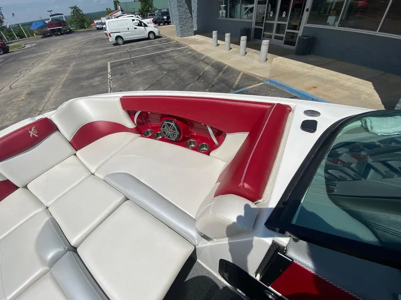 Slide: The Image of 2017 MasterCraft X26 boat interior with red and white seating, parked outside a building. - 28