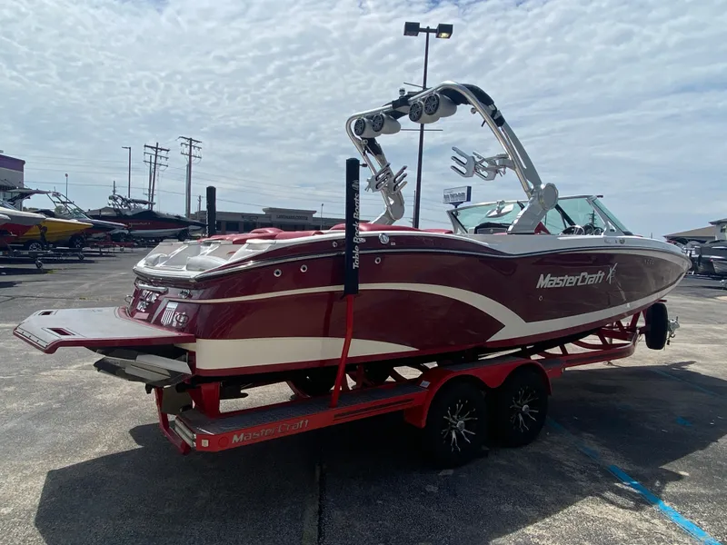 Slide: The Image of 2017 MasterCraft X26 boat on trailer, red and white design, parked outdoors. - 5