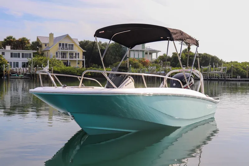 Slide: The Image of 2024 Boston Whaler 160 Super Sport boat on calm water, with houses in the background. - 15