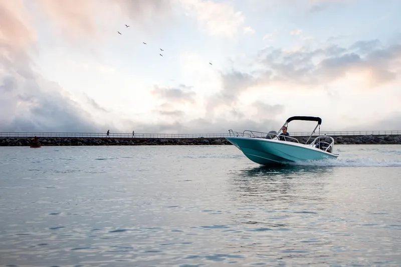 Slide: The Image of 2024 Boston Whaler 160 Super Sport cruising on calm waters at sunset. - 16