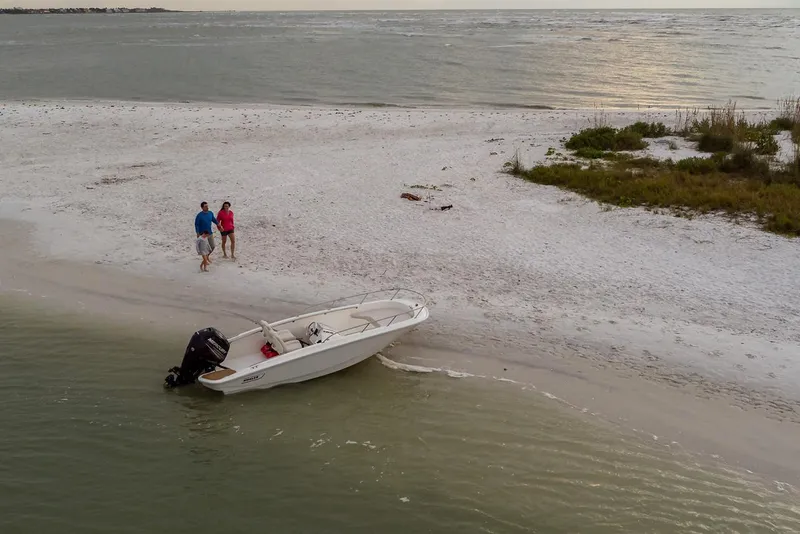Slide: The Image of 2024 Boston Whaler 160 Super Sport on sandy beach with two people nearby. - 23