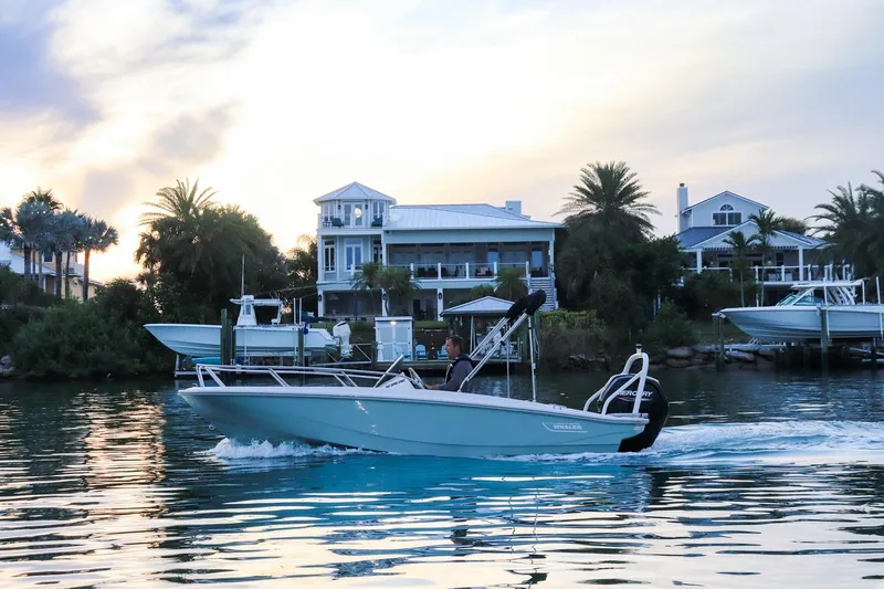 Slide: The Image of 2024 Boston Whaler 160 Super Sport cruising near waterfront homes at sunset. - 5