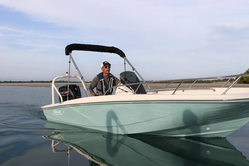 Slide: The Image of 2024 Boston Whaler 160 Super Sport boat on calm water with driver. - 9