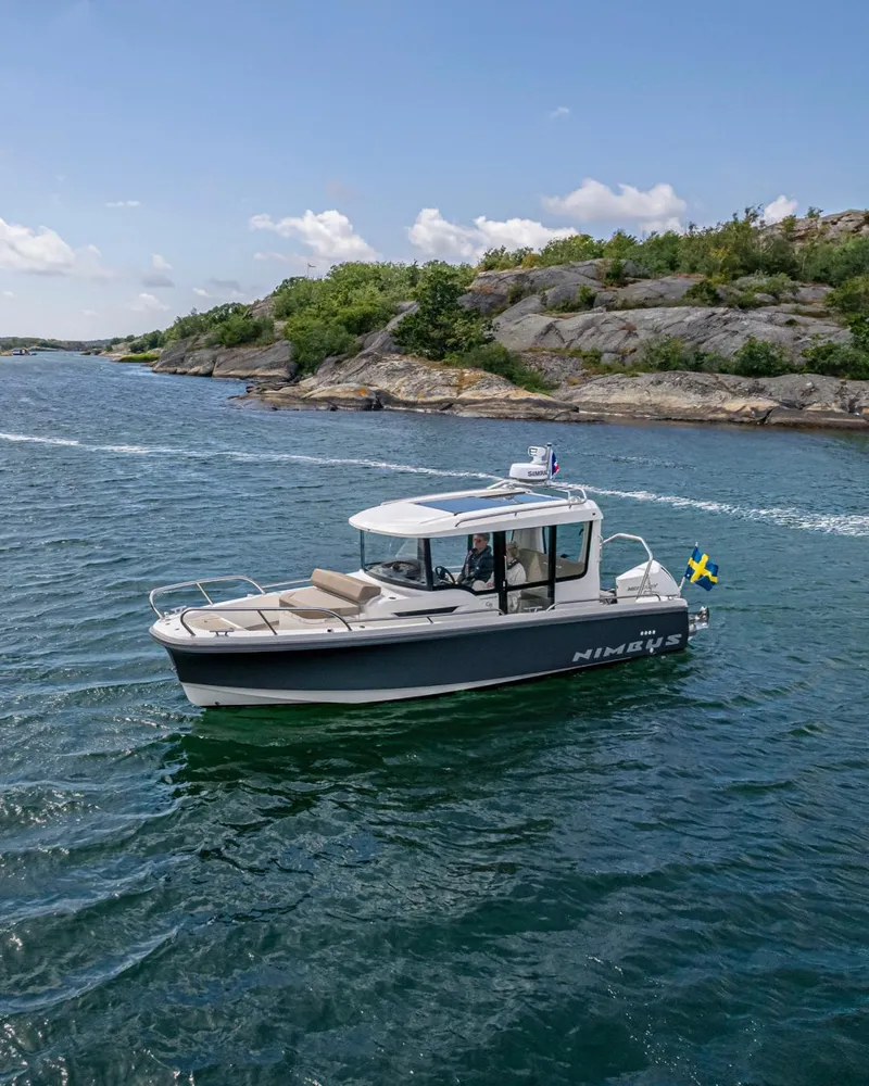 Slide: The Image of 2024 Nimbus C8 boat cruising on a scenic lake with rocky shoreline. - 15