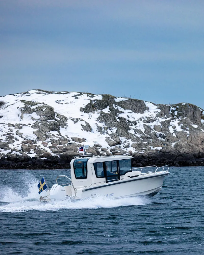 Slide: The Image of 2024 Nimbus C8 boat cruising near snowy rocky shoreline. - 20