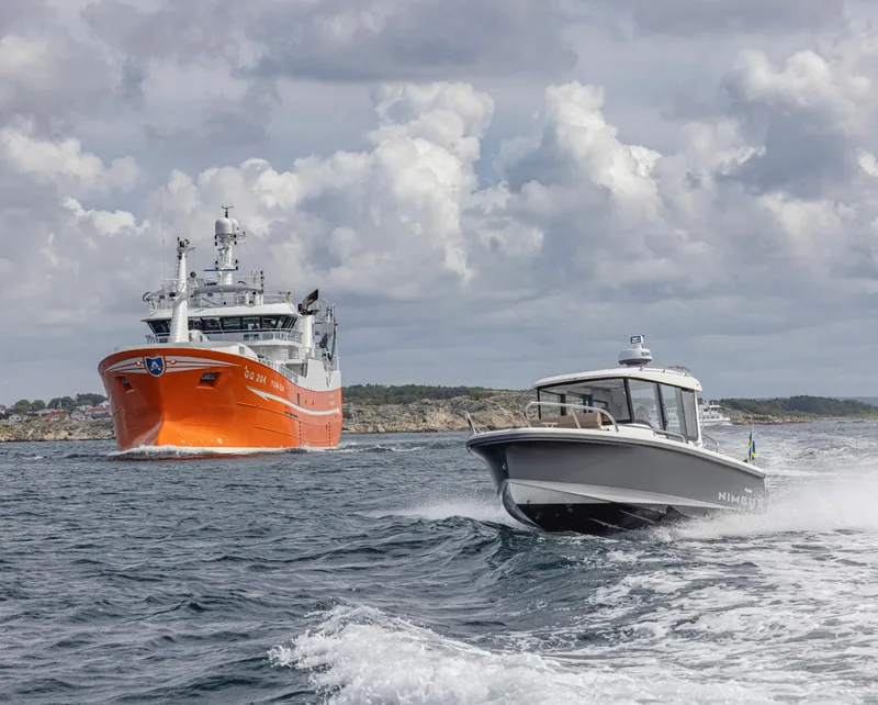Slide: The Image of Nimbus C8 2024 model cruising near a large orange ship on a cloudy day. - 21