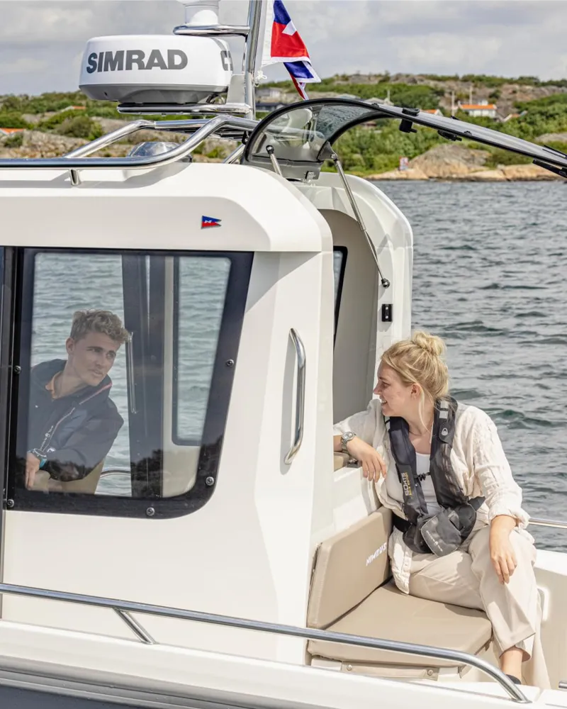 Slide: The Image of 2024 Nimbus C8 boat with two people enjoying a scenic water view. - 32