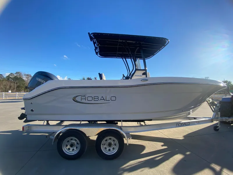 Slide: The Image of 2024 Robalo R200 Center Console boat on a trailer under a clear blue sky. - 2